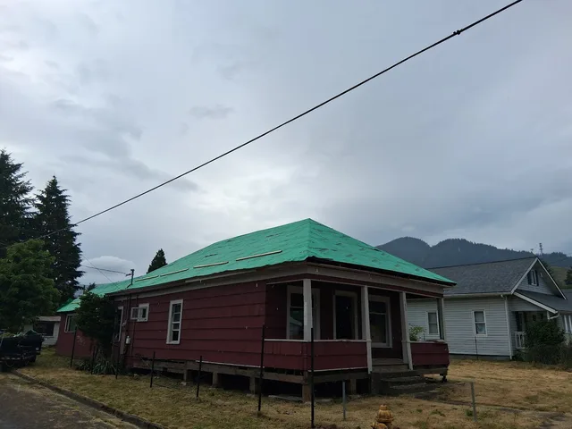 House re-roof at the underlayment stage with green synthetic wrap